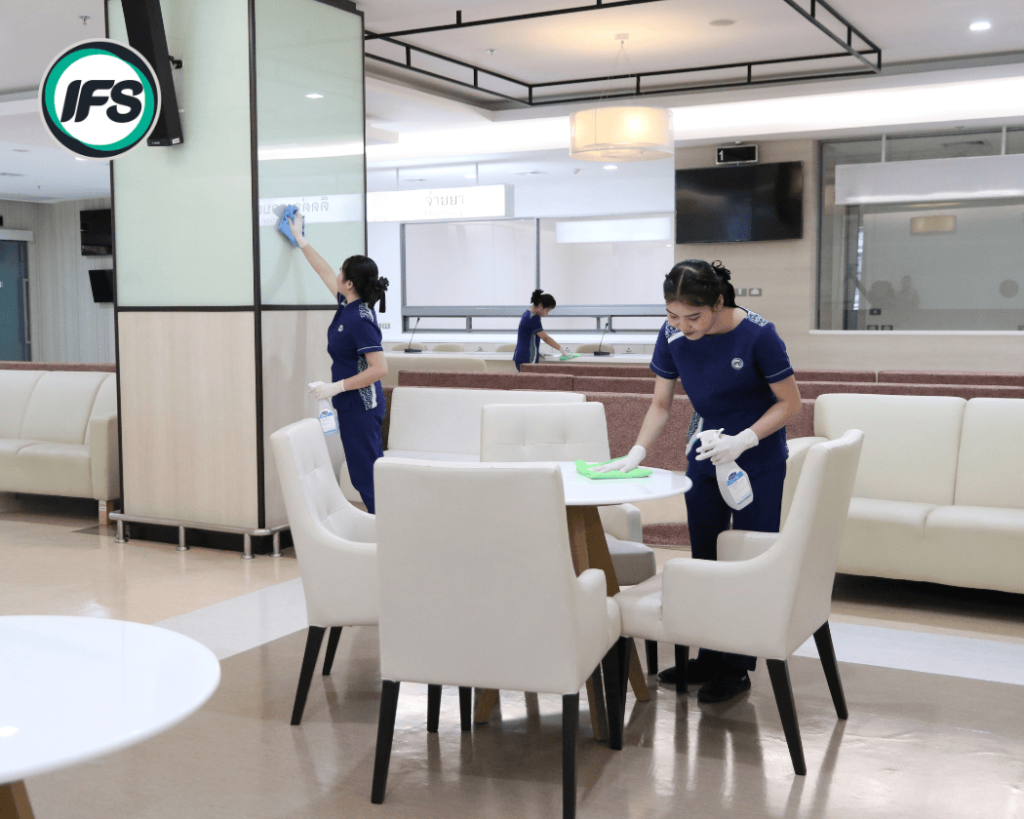 เจ้าหน้าที่ทำความสะอาดของ IFS Thailand กำลังเช็ดทำความสะอาดโต๊ะ เก้าอี้ และผิวสัมผัสในพื้นที่บริการของอาคารด้วยน้ำยาฆ่าเชื้อ เพื่อรักษาความสะอาดและสุขอนามัยตามมาตรฐานระดับสากล