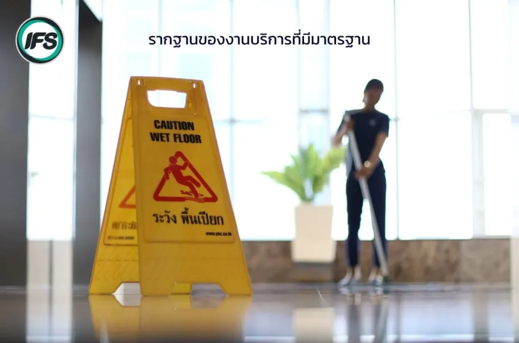 ป้ายเตือนพื้นเปียกหน้าพื้นที่ทำความสะอาด ขณะพนักงานกำลังถูพื้นภายในอาคาร สื่อถึงมาตรฐานความปลอดภัยและความเป็นมืออาชีพในการให้บริการ